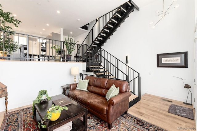living area with recessed lighting, visible vents, stairs, wood finished floors, and a high ceiling