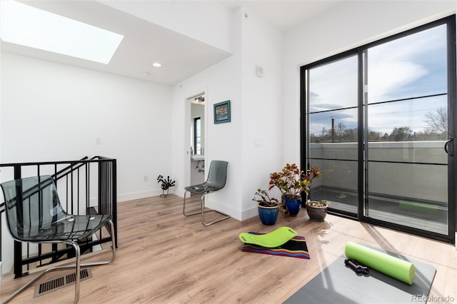 exercise area featuring a skylight, visible vents, recessed lighting, light wood-style flooring, and baseboards