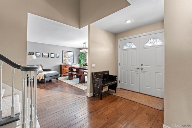 foyer featuring wood-type flooring, stairs, baseboards, and a notable chandelier