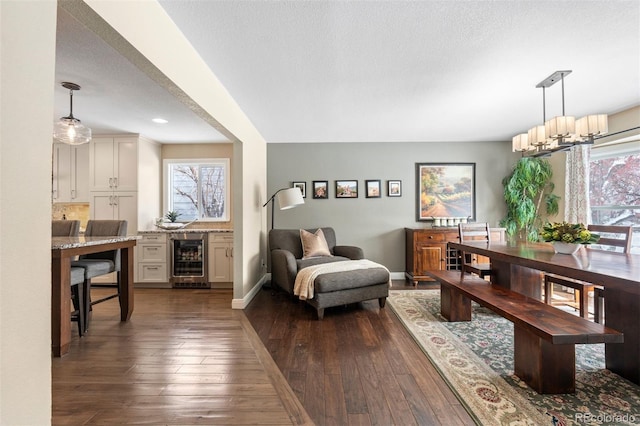 dining area with a healthy amount of sunlight, beverage cooler, baseboards, and dark wood finished floors