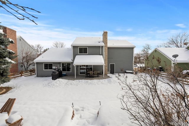 snow covered back of property with fence