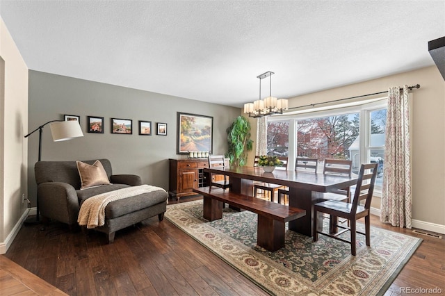 dining space with dark wood-style floors, a chandelier, a textured ceiling, and baseboards