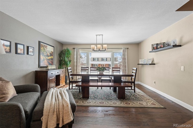 dining area with a chandelier, dark wood-style flooring, a textured ceiling, and baseboards