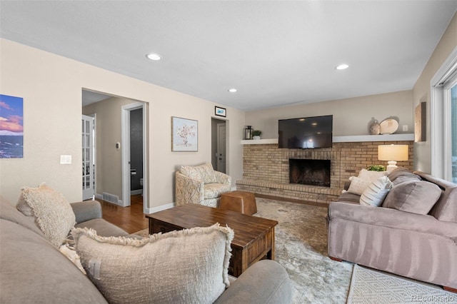 living room featuring recessed lighting, wood finished floors, visible vents, baseboards, and a brick fireplace