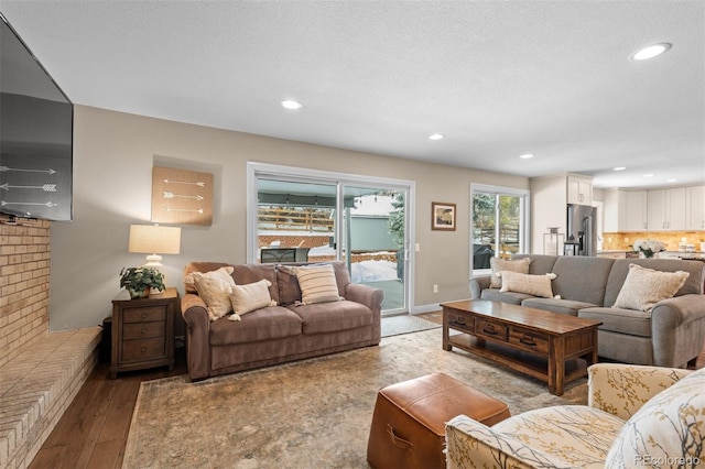 living area featuring baseboards, a textured ceiling, wood finished floors, and recessed lighting