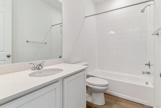 full bathroom with vanity, hardwood / wood-style floors, tiled shower / bath combo, and toilet