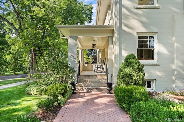 doorway to property featuring covered porch and brick siding