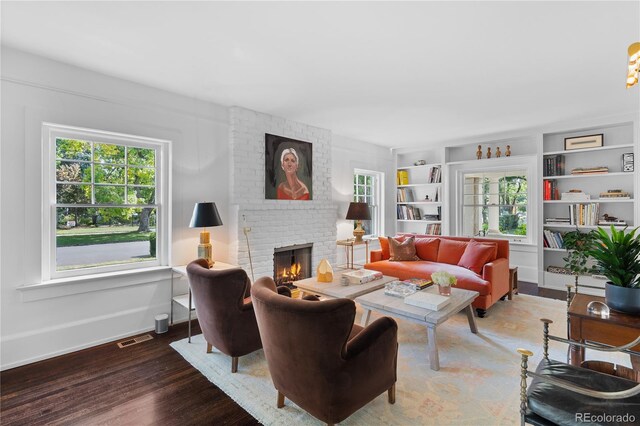 living room featuring plenty of natural light, a fireplace, built in features, and dark wood-style flooring