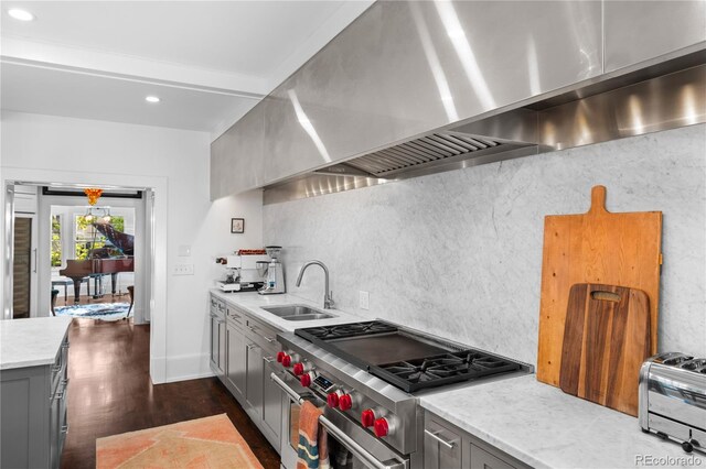 kitchen featuring tasteful backsplash, gray cabinetry, a sink, high end range, and extractor fan