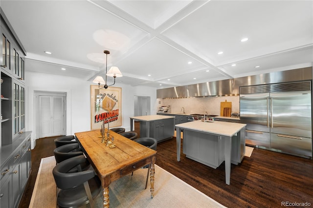 kitchen with a breakfast bar area, built in fridge, gray cabinetry, light countertops, and an island with sink