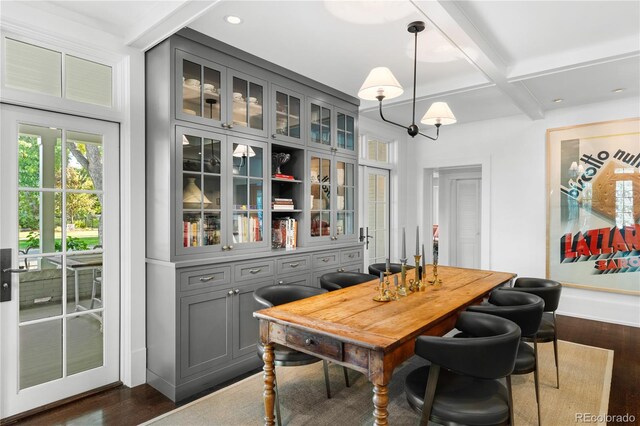 dining area with dark wood-type flooring, a chandelier, coffered ceiling, and beamed ceiling