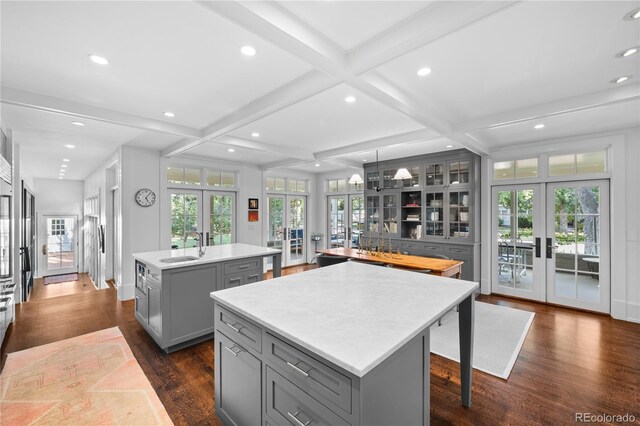 kitchen featuring french doors, gray cabinets, light countertops, hanging light fixtures, and an island with sink