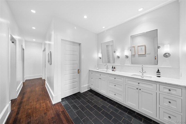 full bath with double vanity, baseboards, a sink, and recessed lighting