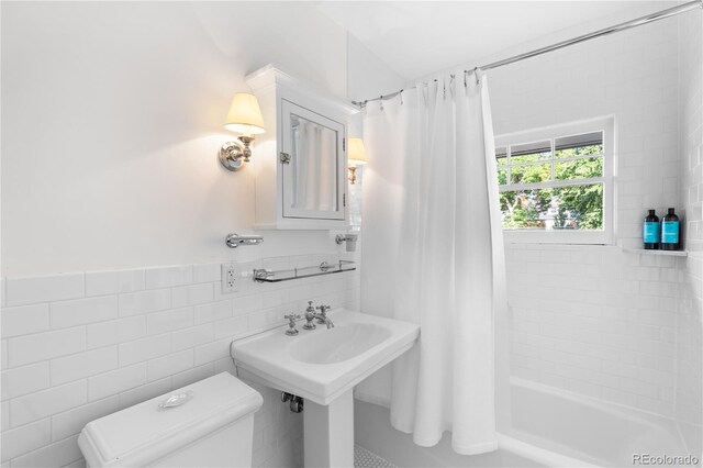 full bath with toilet, shower / bath combo with shower curtain, tile walls, and wainscoting