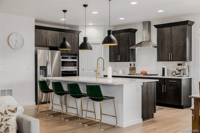 4465 Mesa Top Dr, Monument, CO 80132 - kitchen with appliances with stainless steel finishes, wall chimney exhaust hood, light countertops, decorative backsplash, and light wood-type flooring