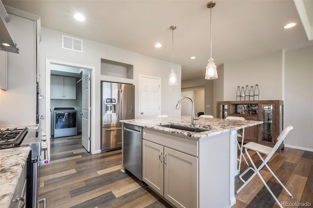 6362 Lythmore Grv, Colorado Springs, CO 80927 - kitchen with stainless steel appliances, a sink, washer / clothes dryer, dark wood-type flooring, and wall chimney range hood