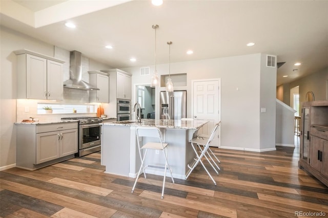 6362 Lythmore Grv, Colorado Springs, CO 80927 - kitchen with appliances with stainless steel finishes, wall chimney range hood, dark wood finished floors, decorative backsplash, and a kitchen bar