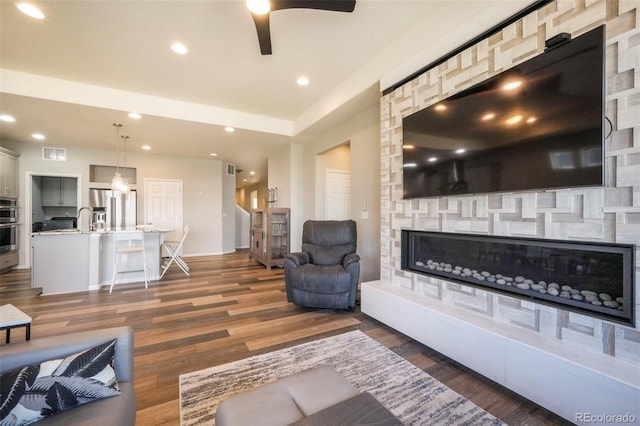 6362 Lythmore Grv, Colorado Springs, CO 80927 - living room featuring wood finished floors, a stone fireplace, a ceiling fan, baseboards, and recessed lighting