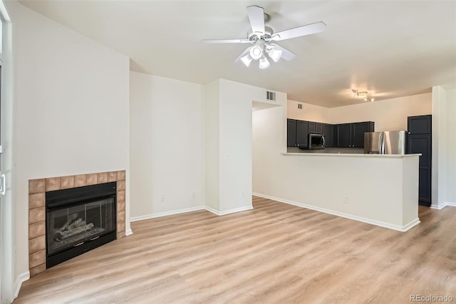 8500 E Jefferson Unit 3C, Denver, CO 80237 - unfurnished living room featuring a ceiling fan, light wood-type flooring, a tile fireplace, and baseboards