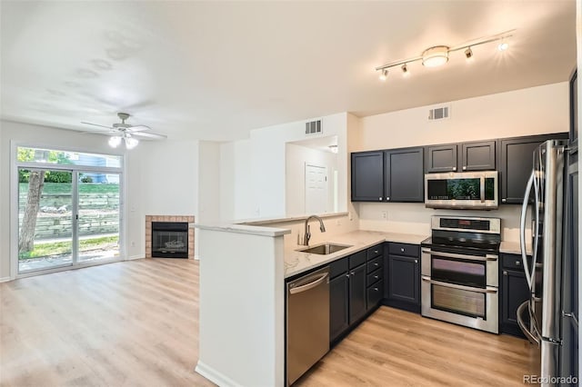 8500 E Jefferson Unit 3C, Denver, CO 80237 - kitchen featuring stainless steel appliances, a sink, a tile fireplace, a ceiling fan, and a peninsula