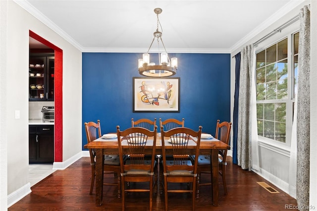 dining area with a notable chandelier, baseboards, visible vents, and ornamental molding