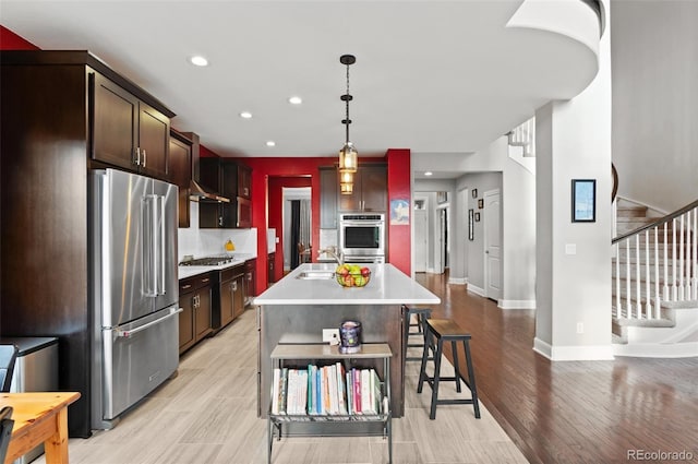 kitchen with baseboards, a sink, light countertops, recessed lighting, and stainless steel appliances