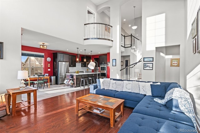 living room with stairway, a towering ceiling, and wood finished floors