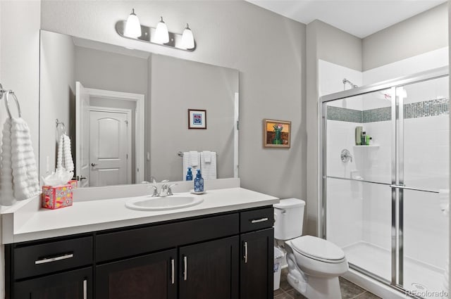 bathroom with tile patterned floors, toilet, vanity, and a stall shower