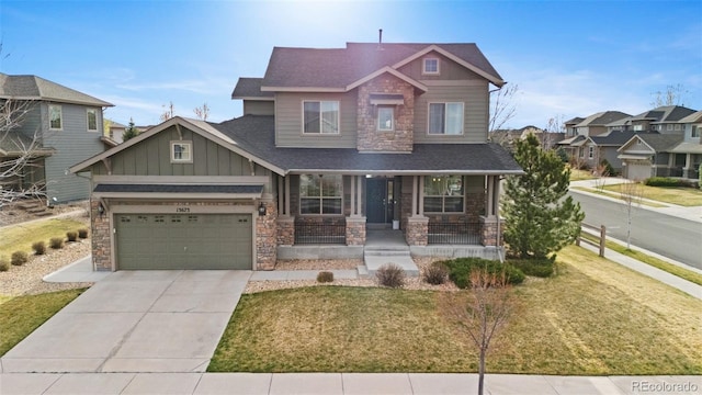 craftsman-style home with a front yard, a porch, stone siding, board and batten siding, and driveway