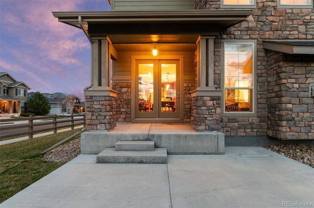 view of exterior entry with a residential view, stone siding, and fence