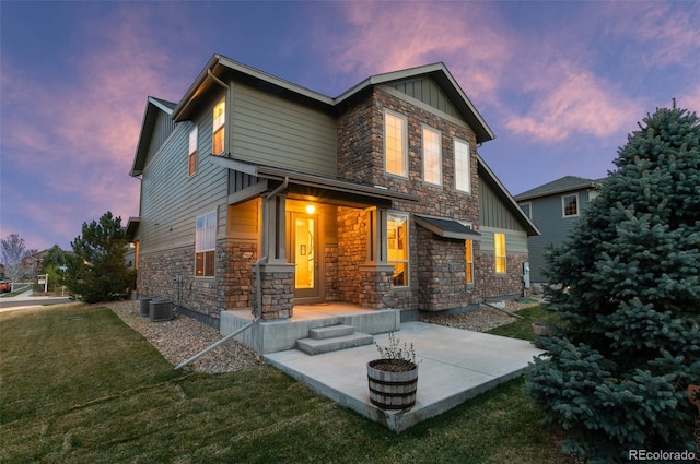 back of property with a yard, board and batten siding, and stone siding