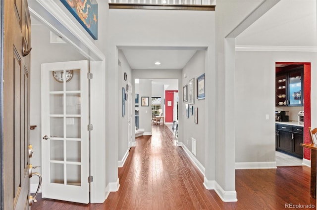 foyer featuring baseboards, crown molding, and wood finished floors