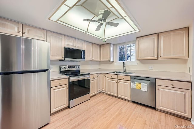 kitchen with appliances with stainless steel finishes, ceiling fan, sink, light brown cabinets, and light hardwood / wood-style floors