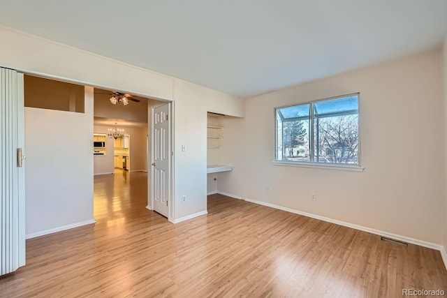 spare room featuring a notable chandelier and light hardwood / wood-style flooring