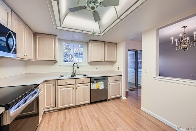 kitchen with appliances with stainless steel finishes, ceiling fan with notable chandelier, sink, light brown cabinets, and light hardwood / wood-style floors