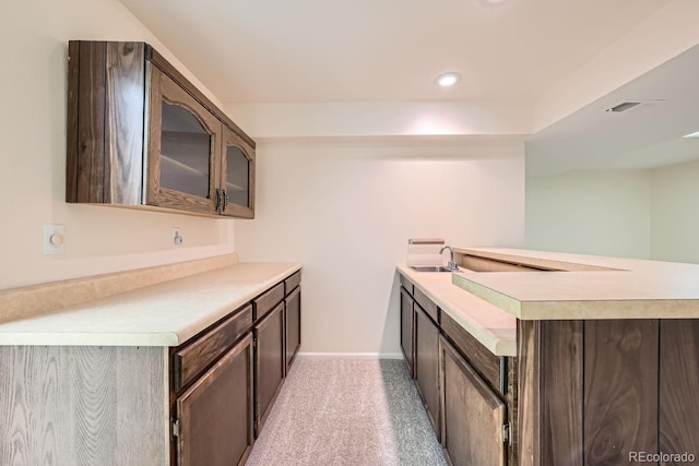 kitchen with kitchen peninsula, dark brown cabinetry, and sink