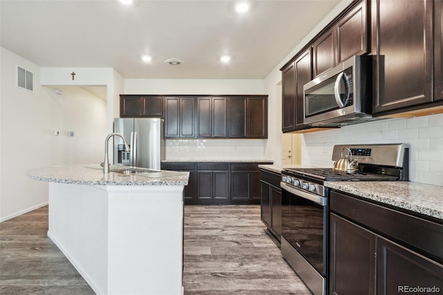 kitchen with dark brown cabinetry, sink, a kitchen island with sink, stainless steel appliances, and light hardwood / wood-style floors