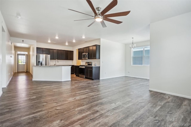 kitchen with sink, dark hardwood / wood-style flooring, hanging light fixtures, stainless steel appliances, and a center island with sink