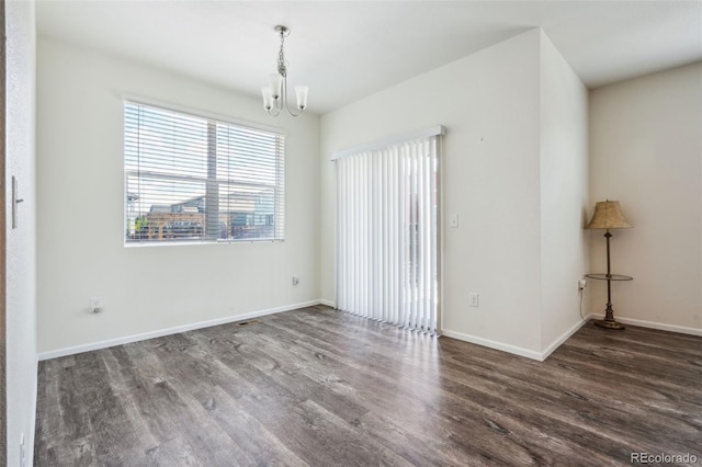 unfurnished room with an inviting chandelier and dark hardwood / wood-style floors