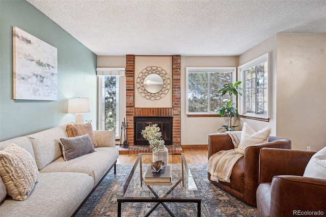 living room with hardwood / wood-style flooring, a brick fireplace, and a textured ceiling