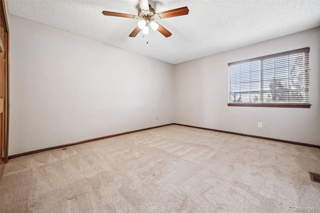 carpeted empty room with ceiling fan and a textured ceiling