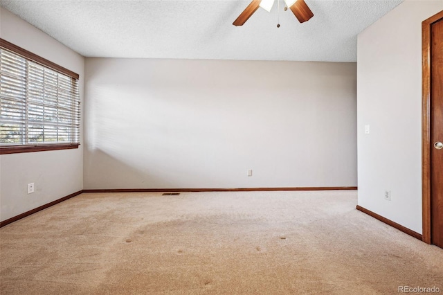 unfurnished room with ceiling fan, light carpet, and a textured ceiling