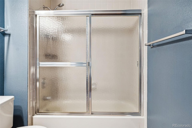 bathroom with toilet and combined bath / shower with glass door