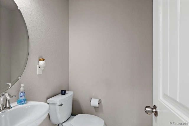 half bath featuring toilet and a sink