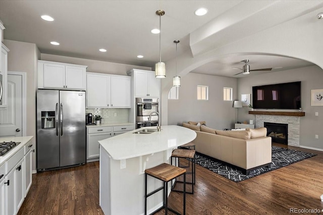 kitchen featuring a sink, ceiling fan, appliances with stainless steel finishes, and arched walkways