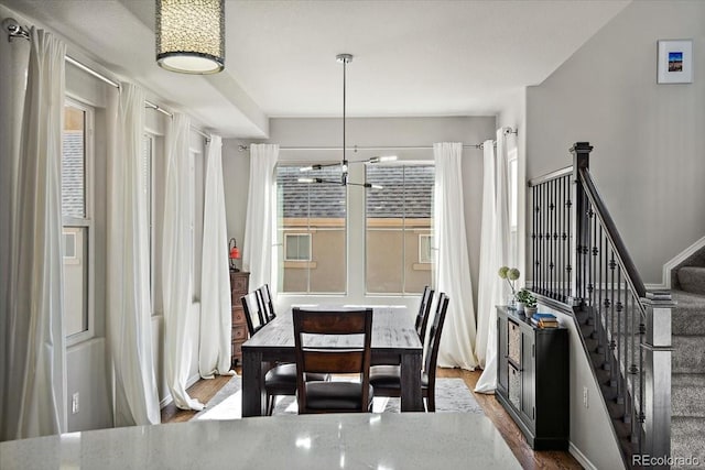 dining area featuring stairway, a notable chandelier, and wood finished floors