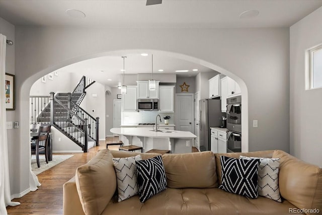 living area with arched walkways, recessed lighting, wood finished floors, stairs, and baseboards