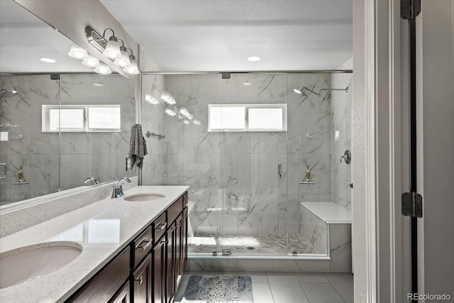 full bath with double vanity, a sink, and a marble finish shower