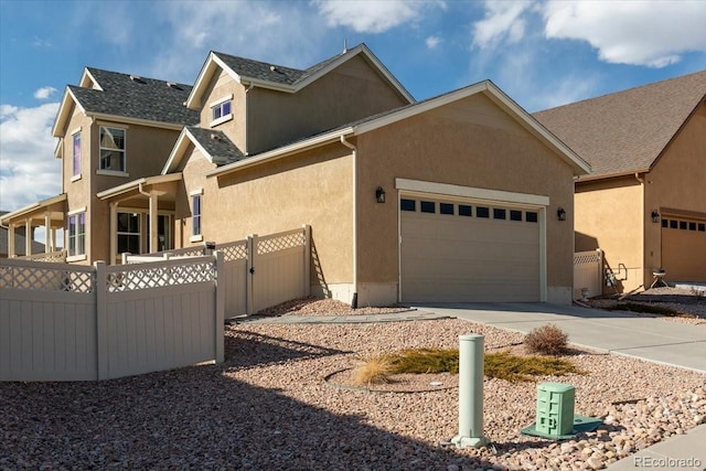 view of property exterior featuring a garage, fence, stucco siding, a gate, and driveway