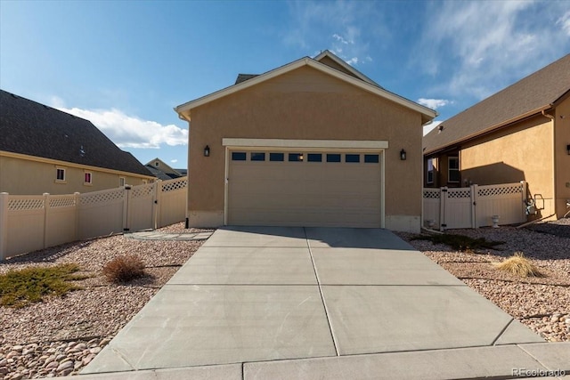 view of front of house with fence, stucco siding, a gate, and concrete driveway